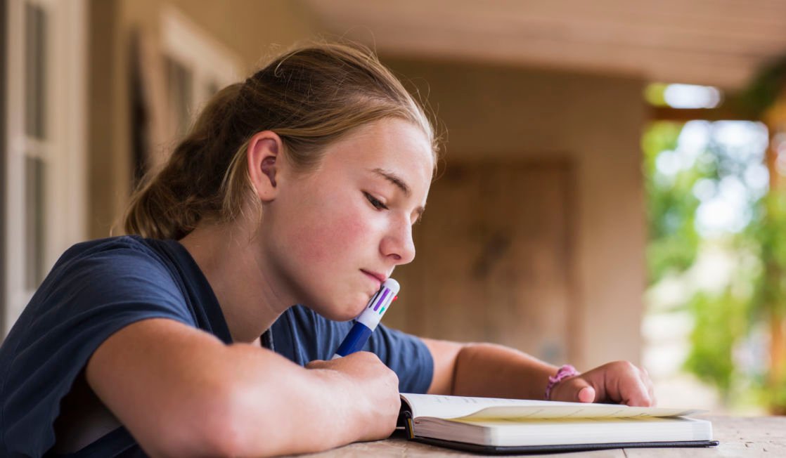 13 year old girl reading and writing in her diary